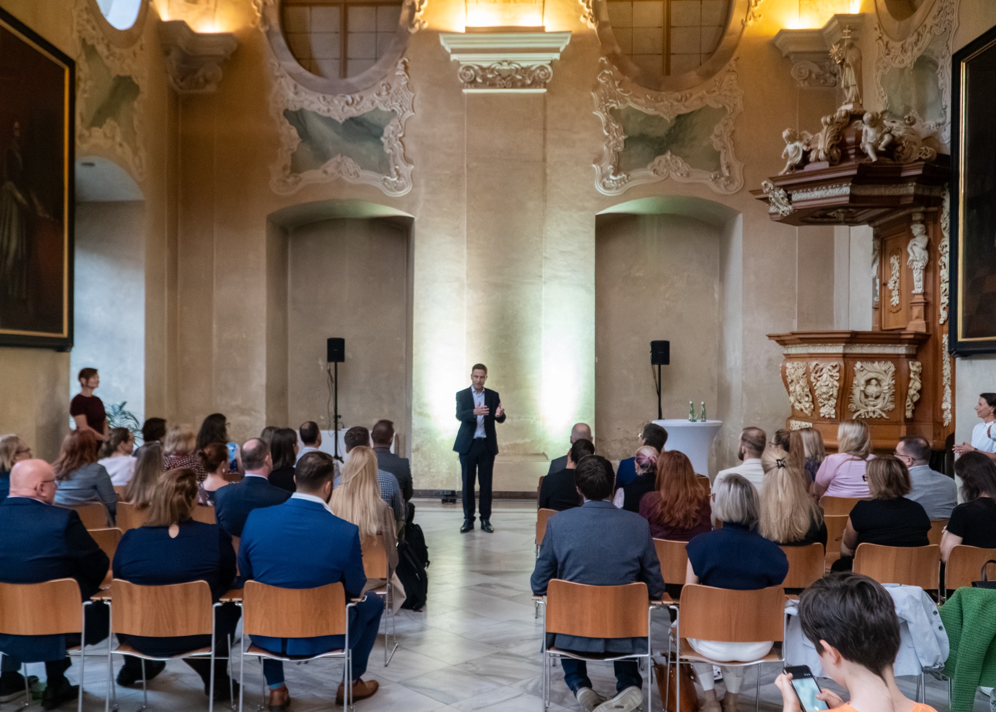 Guests listening to a speaker in the historic hall at Strahov Monastery